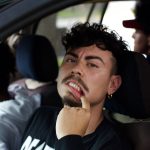 Man in car pulling on lower lip