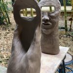 Off-centered photo of two face sculptures with rectangular eyes staring at each other