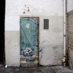 Photo of chipping wall that includes painting of welcoming blue door