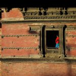 Woman standing in window of large brick building