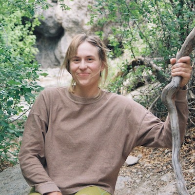 Headshot of Hannah Hazel against a river in a brown sweater.