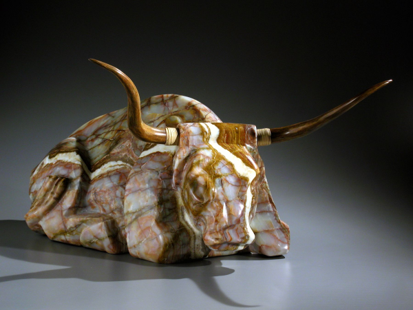 Photograph of a sculpted bull against a grey background.