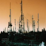 Photograph of radio towers against an oranges sky