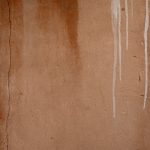 Photograph of an orange wall with white paint and waterstains running down