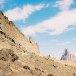 Photograph of Shiprock in New Mexico against a blue sky with clouds