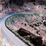 Photograph of a highway cutting in a curve through the side of a mountain.