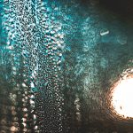 Blue, textured, abstract image with circular, bright light to the right