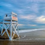 Photograph of deserted beach with lifeguard chair and blue sky
